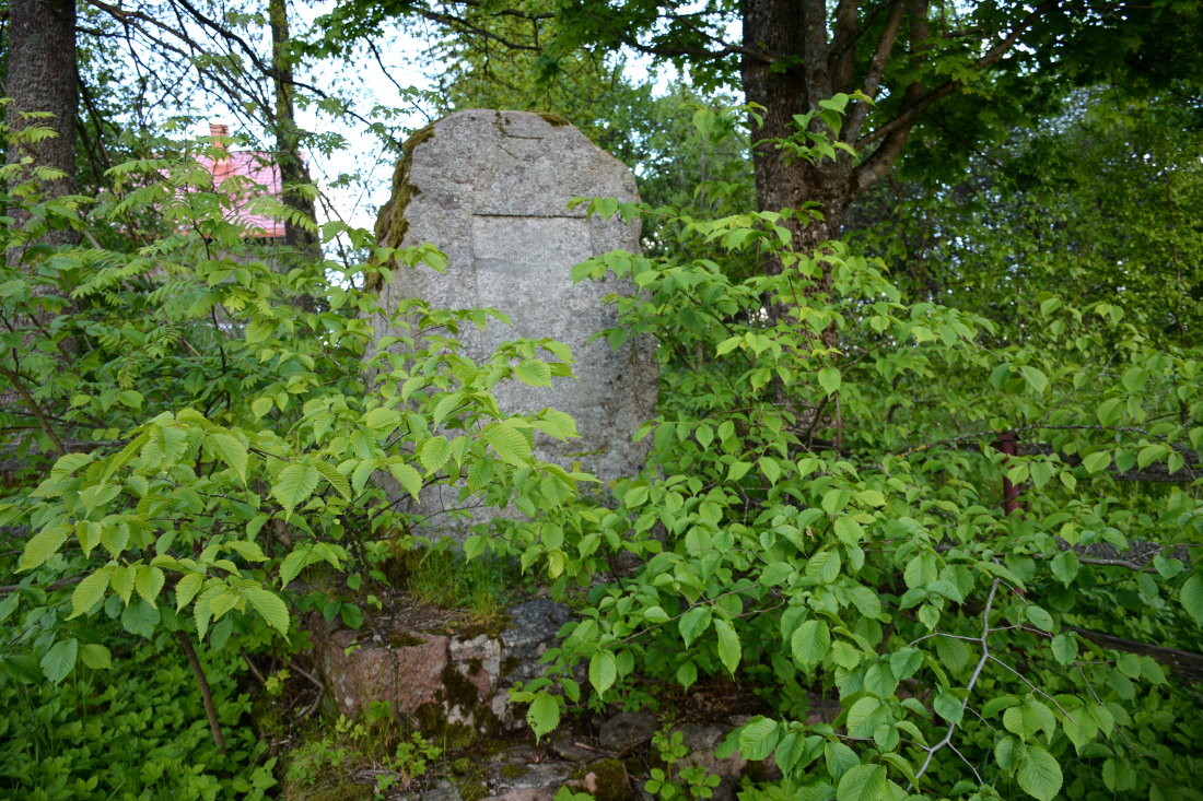 Kamienny pomnik wśród drzew.