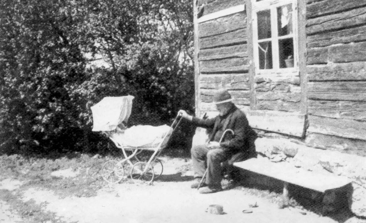 Starszy mężczyzna siedzi na ławce przed domem.