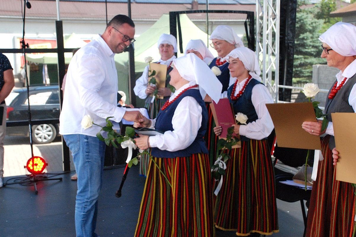 Na scenie męźczyzna wręcza kobietom proezenty.