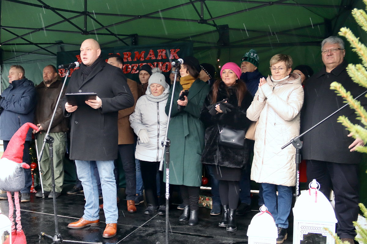 Grupa dorosłych stoi na scenie pod namiotem.