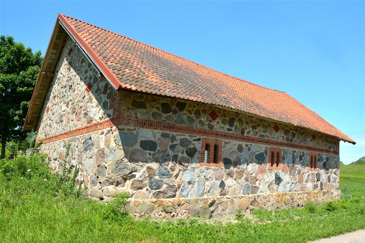 Budynek z kamieni polnych. Dach pokryty dachówką.