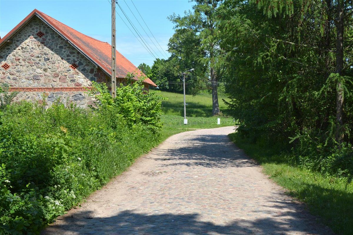 Budynek z kamieni polnych. W środku droga kamienna.