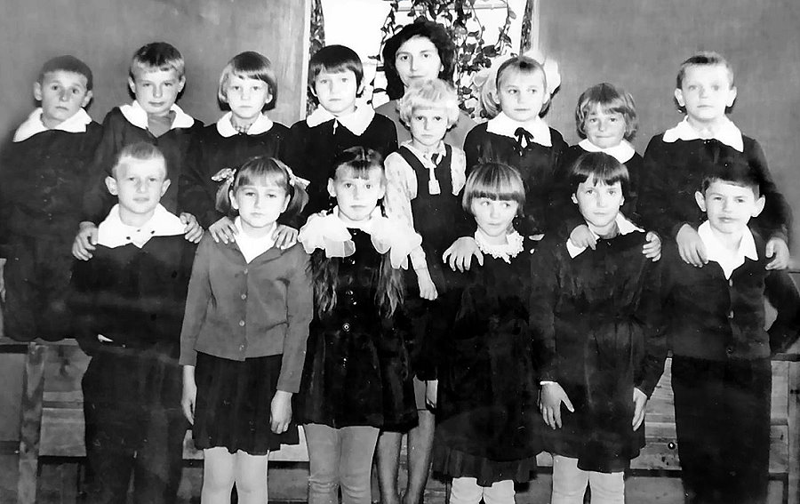 Duża grupa dzieci pozuje do fotografii. W środku nauczycielka.