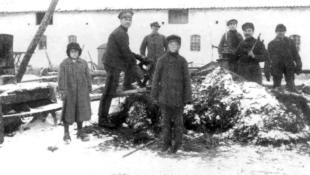 Rosyjscy jeńcy wojenni pracujący na zewnątrz przy stercie ziemi lub nawozu.