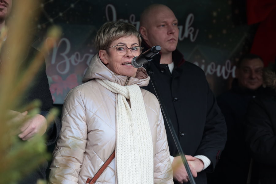 Kobieta przemawiająca na scenie podczas wydarzenia świątecznego; obok stoi mężczyzna.