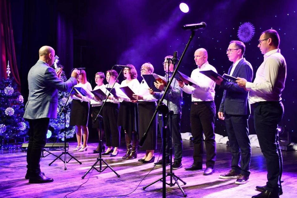 Grupa wokalna z dyrygentem występująca na scenie podczas koncertu.