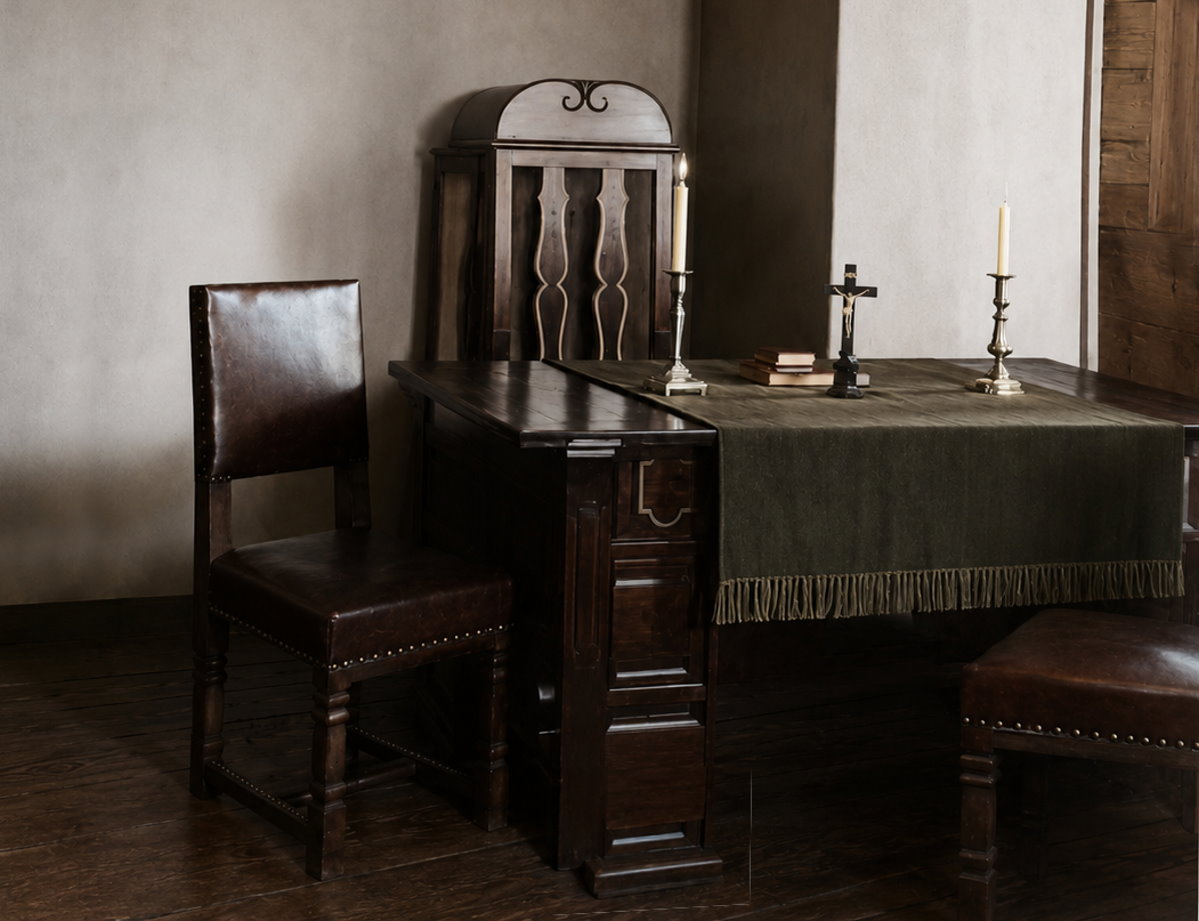 Wyposażenie zakrystii kościoła w Wieliczkach po modernizacji z 1927 roku: drewniane biurko, wyściełany fotel, krzesło oraz krzyż ustawiony na blacie.