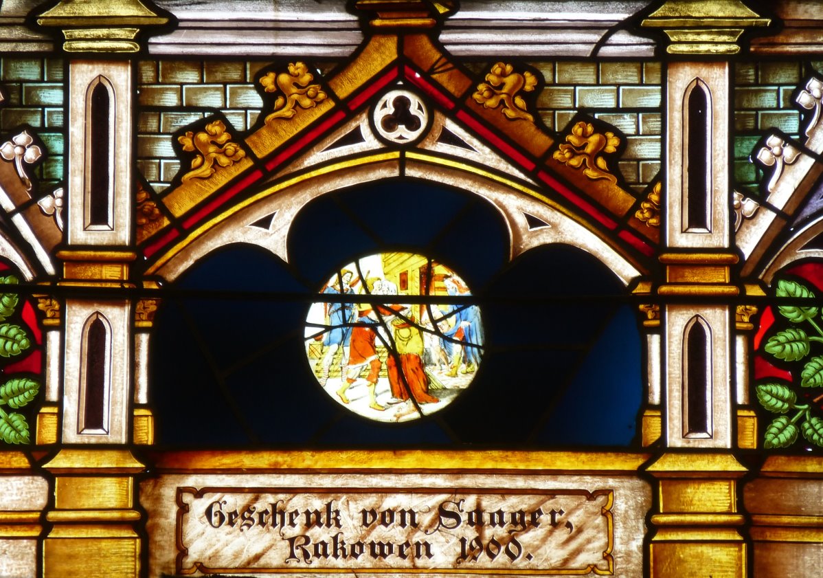 Zbliżenie g&oacute;rnej części witraża z dekoracyjną architekturą i okrągłym medalionem we wnętrzu kościoła w Rożyńsku Wielkim.