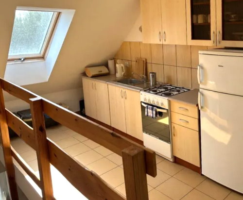 Wnętrze kuchni. Na środku stół po prawej lodówka.